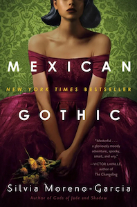 A young Mexican woman is standing or sitting on the cover visible from the nose down wearing a red dress that wraps around her chest with no shoulders. She has her hands in her lap holding a bouquet of yellow flowers. The background is green wallpaper with floral designs.